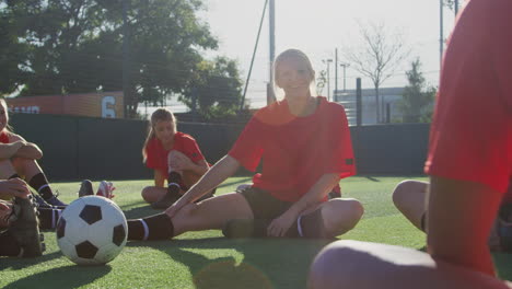 Female-Soccer-Team-Warming-Up-With-Stretches-In-Training-Against-Flaring-Sun