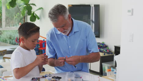 Hispanic-Grandson-And-Grandfather-Building-Robot-From-Electronic-Components-At-Home-Together