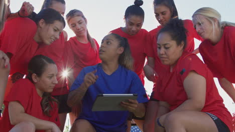 Female-Coach-Discussing-Tactics-With-Womens-Soccer-Team-Using-Digital-Tablet-Before-Match