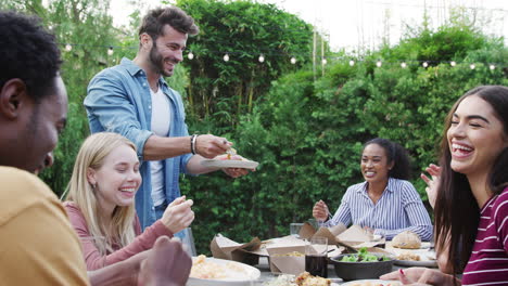 Multi-Cultural-Friends-At-Home-Sitting-At-Table-Enjoying-Food-At-Summer-Garden-Party