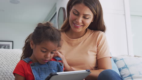 Hispanische-Mutter-Hilft-Ihrer-Tochter-Bei-Der-Heimschule-Und-Macht-Hausaufgaben-Mit-Einem-Digitalen-Tablet
