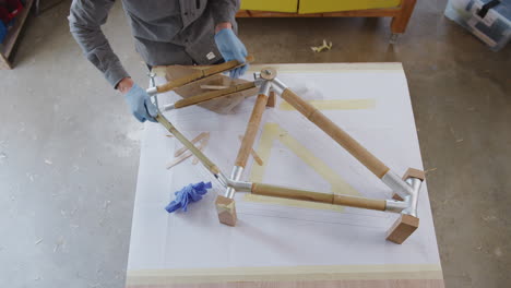 Draufsicht-Eines-Männlichen-Handwerkers-In-Der-Werkstatt,-Der-Handgefertigte,-Nachhaltige-Bambus-Fahrradrahmen-Zusammenbaut