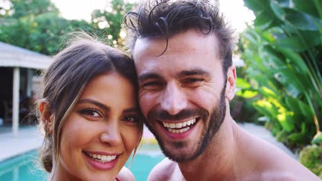 Portrait-Of-Romantic-Hispanic-Couple-Outdoors-With-Friends-Enjoying-Summer-Pool-Party