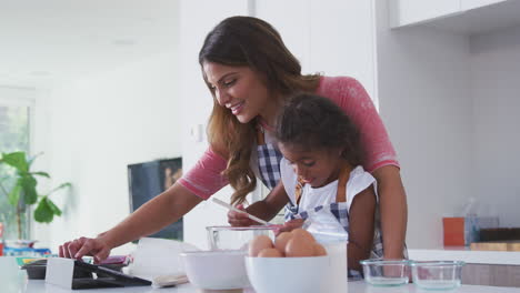 Hispanische-Mutter-Und-Tochter-In-Der-Küche-Folgen-Gemeinsam-Dem-Kuchenrezept-Auf-Einem-Digitalen-Tablet