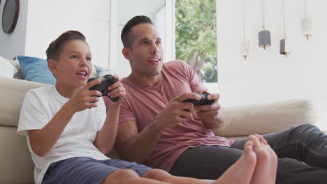 Hispanischer-Vater-Und-Sohn-Sitzen-Zu-Hause-Auf-Dem-Boden-Und-Spielen-Gemeinsam-Videospiele