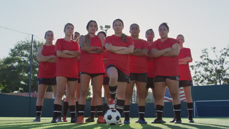 Portrait-Of-Determined-Female-Soccer-Team-With-Ball-On-Training-Ground-Against-Flaring-Sun