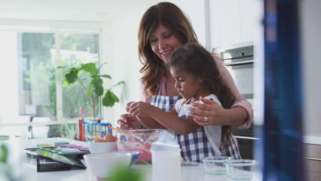 Hispanic-Grandmother-And-Granddaughter-Having-Fun-In-Kitchen-Making-Cake-Together
