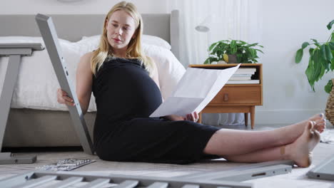 Eine-Schwangere-Mutter-Schaut-Sich-Im-Schlafzimmer-Eine-Anleitung-Zum-Selbstaufbau-Eines-Babybetts-An