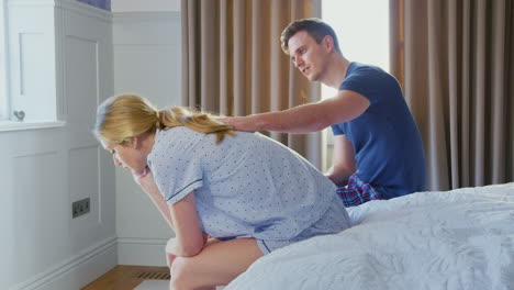 Man-Sitting-On-End-Of-Bed-At-Home-Comforting-Woman-Suffering-With-Mental-Health-Issues