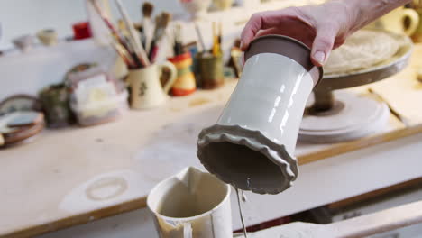 Nahaufnahme-Eines-Männlichen-Töpfers,-Der-Im-Keramikatelier-Glasur-Auf-Eine-Tonvase-Aufträgt
