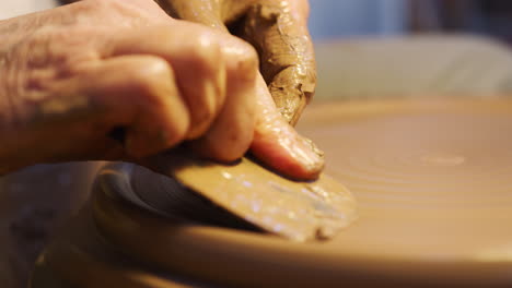 Close-Up-Of-Male-Potter-Shaping-Clay-For-Plate-On-Pottery-Wheel-In-Ceramics-Studio