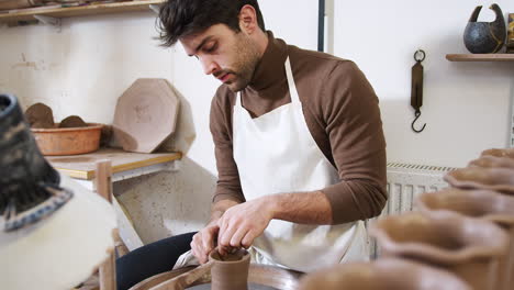 Junger-Mann-Mit-Schürze-Arbeitet-An-Der-Töpferscheibe-Im-Keramikatelier