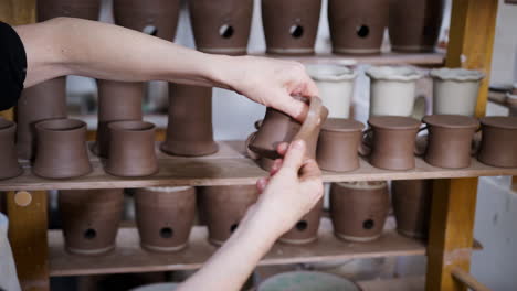 Close-Up-Of-Male-Potter-Fitting-Clay-Handles-To-Mugs-In-Ceramics-Studio