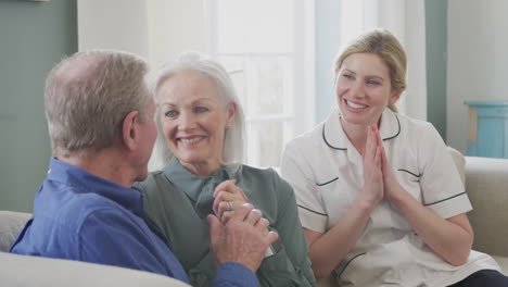 Female-Doctor-Giving-Good-News-To-Senior-Couple-During-Home-Health-Visit