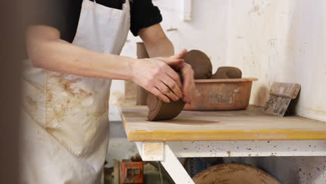 Close-Up-Of-Male-Potter-Rolling-Out-Lump-Of-Clay-In-Ceramics-Studio