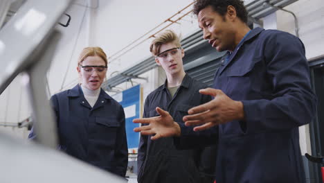 Male-Tutor-With-Students-Looking-At-Car-Engine-On-Auto-Mechanic-Apprenticeship-Course-At-College