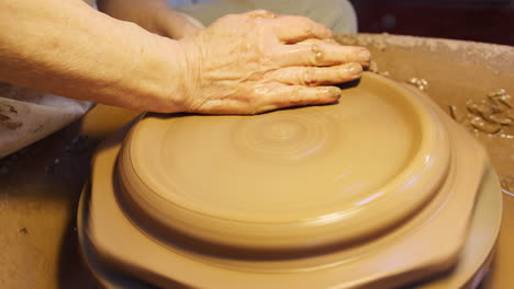 Close-Up-Of-Male-Potter-Throwing-Clay-For-Plate-Onto-Pottery-Wheel-In-Ceramics-Studio