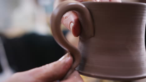 Close-Up-Of-Male-Potter-Fitting-Clay-Handles-To-Mugs-In-Ceramics-Studio