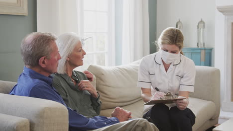 Female-Doctor-With-Mask-Makes-Home-Visit-To-Senior-Couple-For-Medical-Check-During-Covid-19-Lockdown