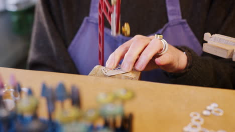Close-Up-Of-Female-Jeweller-Working-On-Brooch-With-Saw-In-Studio