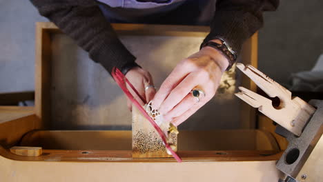 Overhead-Close-Up-Of-Female-Jeweller-Working-On-Brooch-With-Saw-In-Studio