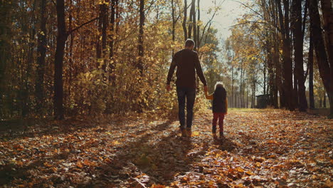 Father-and-children-walking-in-the-park-and-enjoying-the-beautiful-autumn-nature.-Happy-family-on-autumn-walk.-Slow-motion.-High-quality-4k-footage