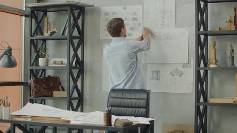 Stylish-office-in-loft-style.-Businessman-makes-notes-on-the-wall.-Business-idea-thinking-design-mind-map.-Designer-works-in-loft-office-and-makes-notes-on-the-drawings-on-the-wall.