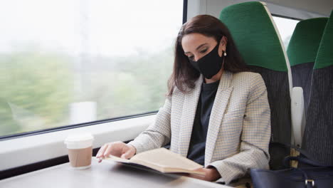 Mujer-De-Negocios-En-Tren-Relajándose-Y-Leyendo-Un-Libro-Usando-Mascarilla-Facial-Ppe-Durante-Una-Pandemia-De-Salud