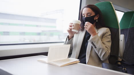 Mujer-De-Negocios-En-Tren-Tratando-De-Tomar-Café-Para-Llevar-A-Través-De-Una-Mascarilla-De-Ppe-Durante-Una-Pandemia-De-Salud