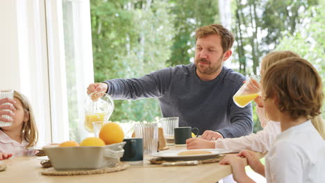 Family-Wearing-Pyjamas-Sitting-Around-Table-Enjoying-Pancake-Breakfast-Together