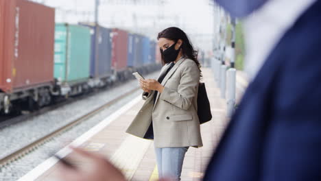 Geschäftspendler-Auf-Dem-Bahnsteig-Mit-Mobiltelefonen,-Die-Während-Einer-Pandemie-PSA-Gesichtsmasken-Tragen