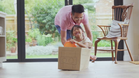 Asian-Father-And-Son-Pushing-Daughter-Around-Kitchen-Floor-At-Home-In-Junk-Modelled-Car