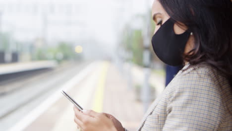 Geschäftspendler-Auf-Dem-Bahnsteig-Mit-Mobiltelefonen,-Die-Während-Einer-Pandemie-PSA-Gesichtsmasken-Tragen