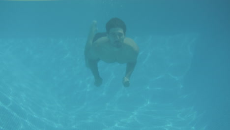 Unterwasseraufnahme-Eines-Mannes,-Der-Eine-Frau-überrascht,-Die-Im-Sommerurlaub-Auf-Einer-Luftmatratze-Im-Schwimmbad-Schwimmt