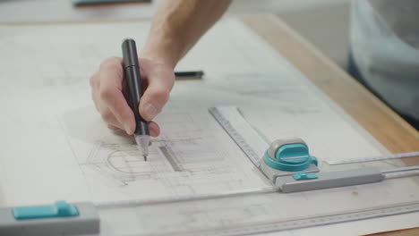 Engineer-draws-buildings-on-the-table-using-a-pencil-and-ruler.-An-architect-creates-a-building-design-on-paper-using-a-marker-and-ruler.