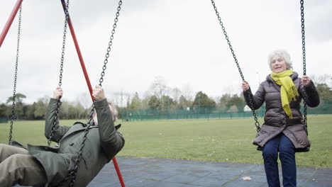Senior-Couple-Having-Fun-Playing-On-Swings-In-Park-Playground