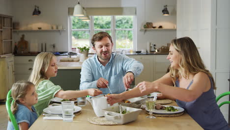 Eltern-Servieren-Essen,-Während-Die-Familie-Zu-Hause-Am-Tisch-Sitzt-Und-Gemeinsam-Das-Essen-Genießt