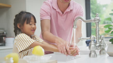 Asiatischer-Vater-Hilft-Seiner-Tochter-Zu-Hause-Beim-Händewaschen-Mit-Seife,-Um-Infektionen-Bei-Einer-Gesundheitspandemie-Zu-Verhindern