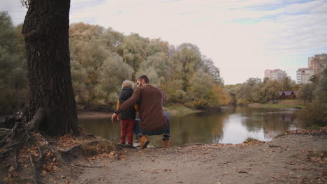 travelling-in-forest-or-park-at-autumn-day-man-is-talking-with-his-little-son-father-and-child-are-enjoying-nature-viewing-lake-in-forest