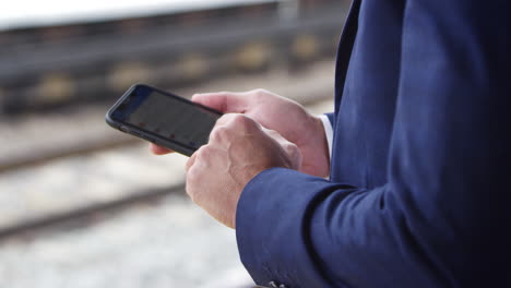 Close-Up-Of-Businessman-On-Railway-Platform-Texting-On-Mobile-Phone