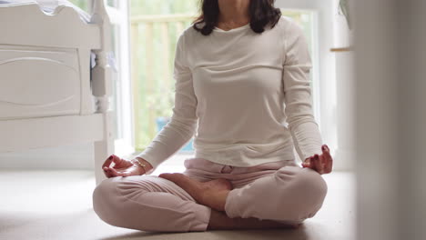 Nahaufnahme-Einer-Reifen-Asiatischen-Frau-Im-Schlafanzug,-Die-Auf-Dem-Boden-Des-Schlafzimmers-Sitzt-Und-In-Yoga-Pose-Meditiert-–-Aufgenommen-In-Zeitlupe