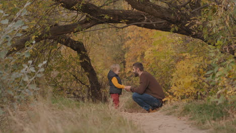 father-and-little-son-are-spending-time-in-picturesque-autumn-forest-walking-and-communicating-together-at-weekend-happy-childhood-and-fatherhood