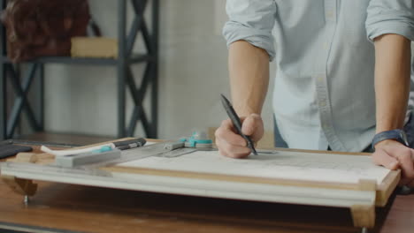 Architect's-desk:-drawings-tape-measure-ruler-and-other-drawing-tools.-Engineer-works-with-drawings-in-a-bright-office-close-up.-Insturments-and-office-for-designer.-Male-hands-draw-with-a-pencil.