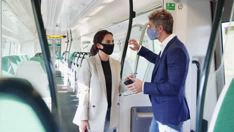Geschäftspendler-Stehen-Während-Der-Pandemie-Mit-Mobiltelefonen-Im-Zugwaggon-Und-Tragen-PSA-Gesichtsmasken