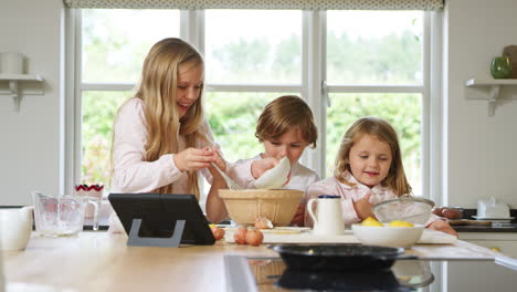 Kinder-Im-Schlafanzug-Backen-In-Der-Heimischen-Küche-Pfannkuchen-Nach-Einem-Rezept-Auf-Einem-Digitalen-Tablet