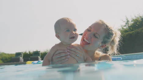 Mother-With-Baby-Daughter-Having-Fun-On-Summer-Vacation-Playing-And-Splashing-In-Swimming-Pool