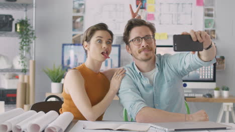 Male-And-Female-Architects-In-Office-Posing-For-Selfie-And-Pulling-Funny-Faces-Together