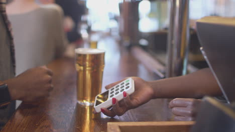 Male-Customer-In-Bar-Making-Contactless-Payment-For-Drinks-With-Smart-Watch-In-Health-Pandemic
