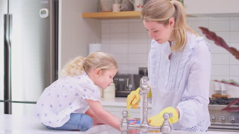 Mutter-Trägt-Gummihandschuhe-Zu-Hause-In-Der-Küche,-Während-Ihre-Kleine-Tochter-Spaß-Beim-Abwaschen-Am-Waschbecken-Hat-–-Aufnahme-In-Zeitlupe