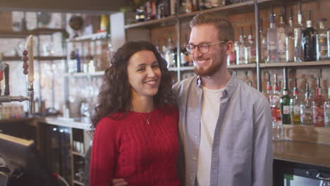 Portrait-Of-Smiling-Couple-Owning-Bar-Standing-Behind-Counter